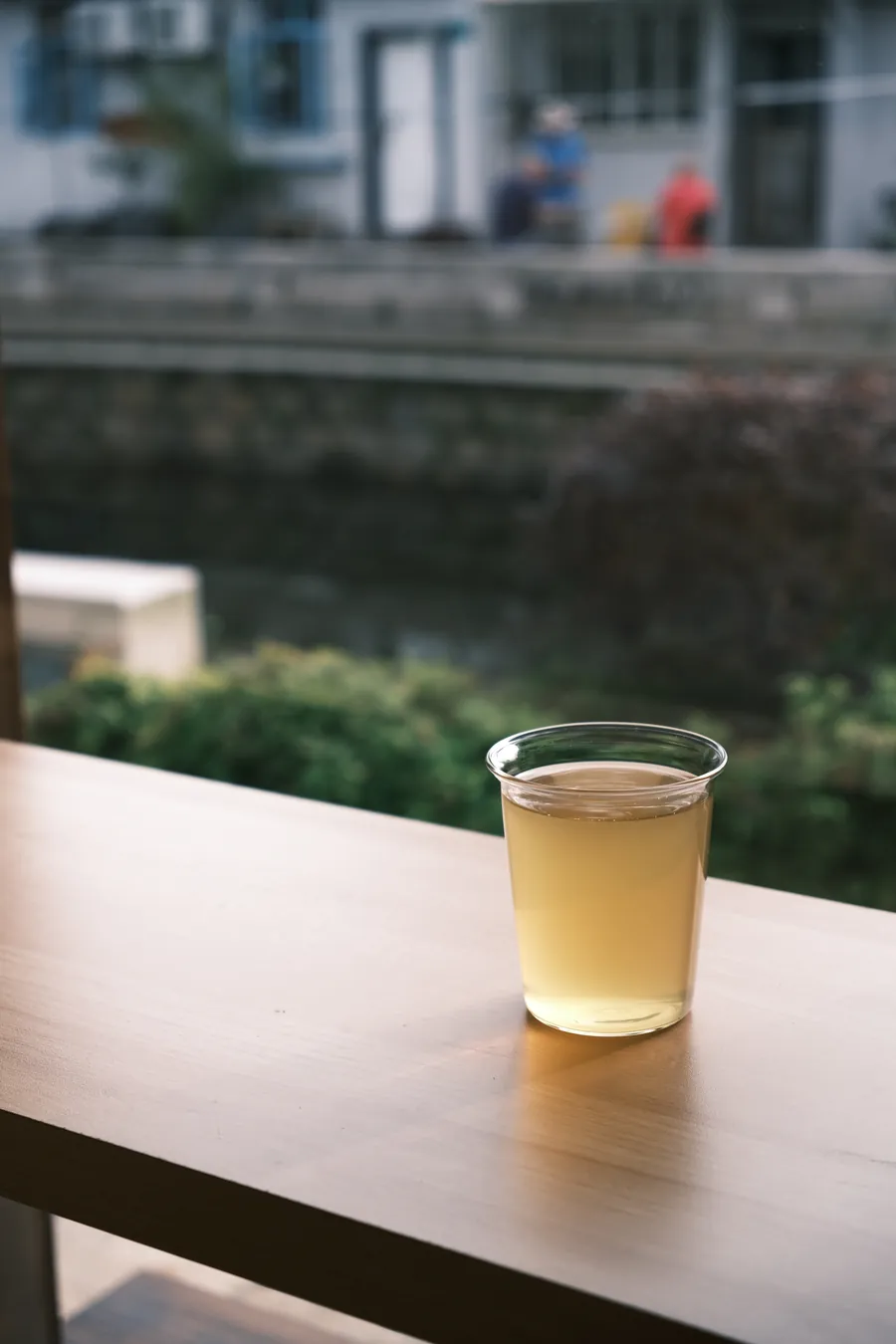 A glass of herbal tea on a window ledge above a canal in Xinchang, Shanghai