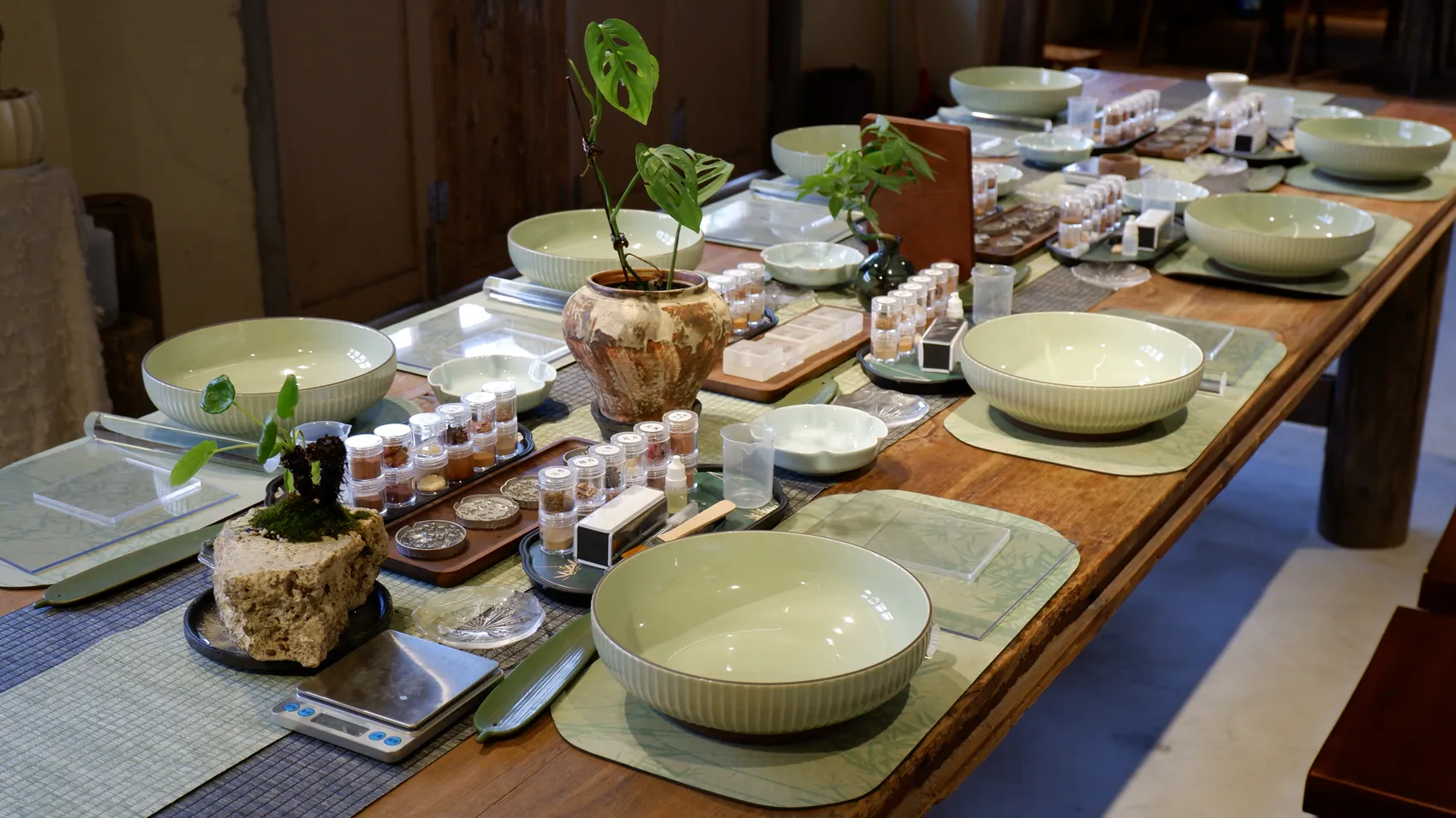 A long village worktable set with celadon bowls, tools and incense materials