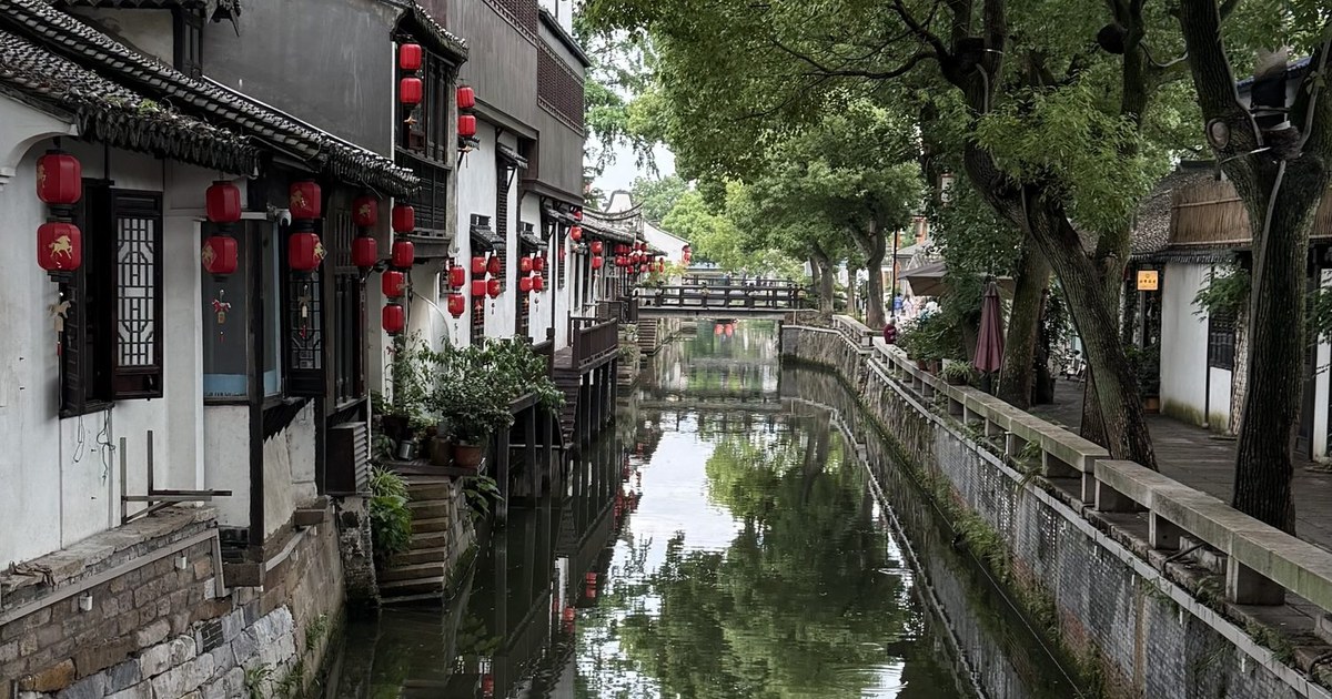 A canal and old shopfronts beneath trees in Xinchang, Shanghai