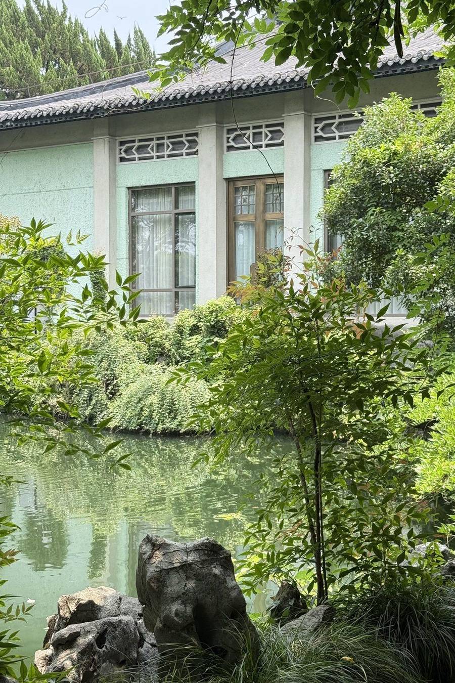 A pond and garden beside a historic building at Zhejiang Xizi Hotel, Hangzhou