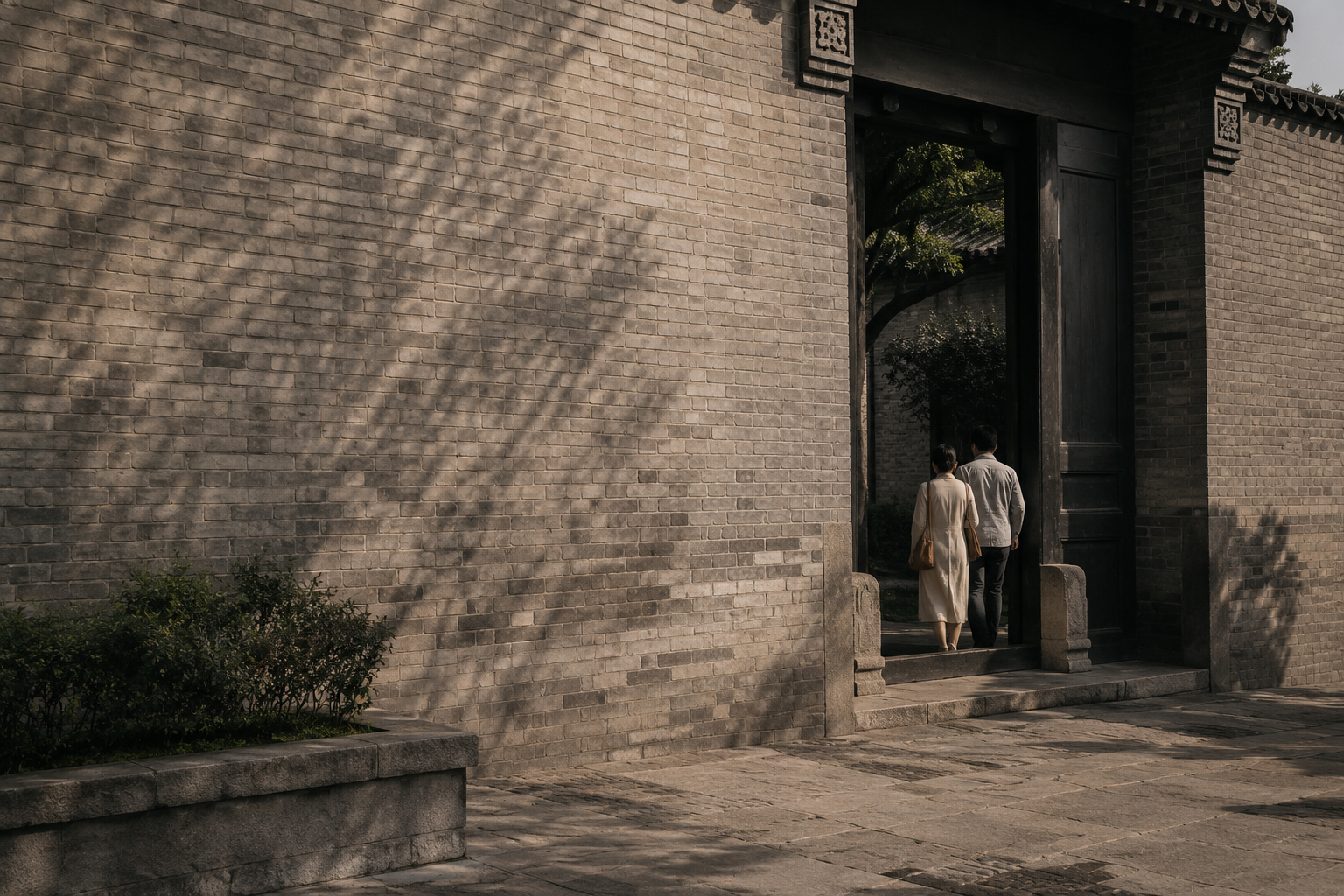 Two travellers entering a traditional stone courtyard gate in late afternoon light